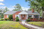 A single-story red brick house at 602 18th Street in Butner features a gabled roof, wooden front door, bushes along the front, a wheelchair-accessible ramp on the right, and a curved concrete walkway leading to the porch.