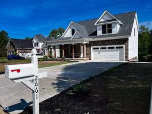 A modern suburban house at 2661 Bowden Drive in Creedmoor features a two-car garage, front porch, and gabled roof behind a white mailbox marked "2661" on a concrete driveway beneath a clear blue sky, with neighboring homes in the background.