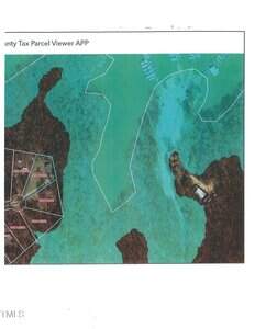 Aerial map showing a coastal area with property parcel boundaries outlined, a group of labeled plots on the left, water in the center and right, and docks or structures visible near the shoreline on the right.