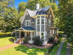 A two-story gray Victorian-style house with white trim at 410 College Street, Oxford, featuring a prominent turret, front porch, manicured lawn, mature trees, and a brick walkway leading to the entrance.