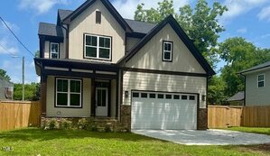A two-story house at 112 First Street, Oxford, with beige siding, dark brown trim, a double garage, and a covered front porch, is surrounded by a wooden fence and green lawn under a partly cloudy sky.