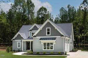 A two-story gray house with white trim and a dark gray roof sits on a landscaped lot at 1224 Red Cedar Court in Youngsville, surrounded by tall trees and green grass under a partly cloudy sky.