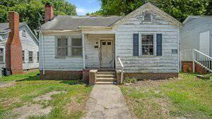 A small, single-story house with weathered white siding at 116 N College Street, Henderson. It has a gable roof, front porch with steps, one shutter missing, and patchy grass in the yard. The house looks aged and in need of repairs.