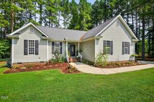 Charming single-story house at 109 N Cinnebar Court in Henderson with light-colored siding, dark shutters, and a gable roof. A curved sidewalk winds to the front door, bordered by landscaped flower beds, lush lawn, and tall trees.