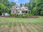 Two-story house at 3718 Sapphire Court, Franklinton, featuring brick and siding exterior, front porch with columns, landscaped yard, PODS storage container on the driveway, surrounded by trees and grass under a blue sky.