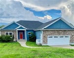 Charming single-story home at 119 Gooch Street in Stem, featuring blue siding, brick accents, a two-car white garage, red front door, and cozy covered porch on a green lawn beneath a partly cloudy sky.
