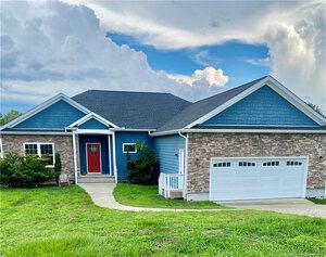 Charming single-story home at 119 Gooch Street in Stem, featuring blue siding, brick accents, a two-car white garage, red front door, and cozy covered porch on a green lawn beneath a partly cloudy sky.