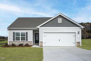 Single-story Oxford home at 1016 Rhino Bend with gray siding, a gabled roof, and a two-car garage. The front yard features green grass and simple shrubs, while a concrete driveway leads up under a partly cloudy sky.