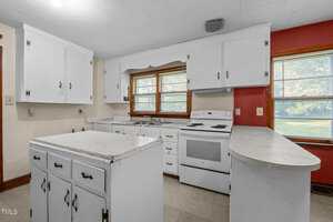 A kitchen with white cabinets and white counter tops.