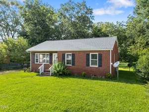 A charming brick house on 412 Cherry Street with a lush lawn and mature trees in the background, nestled in the heart of Oxford.