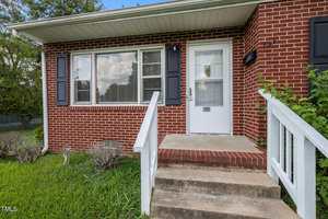 A brick house with a white door and a porch.
