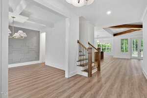 A white and grey room with wood floors and stairs.