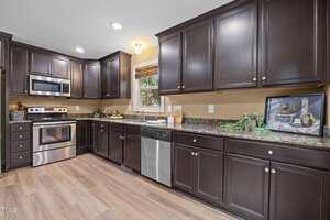 A kitchen with dark cabinets and a stove.