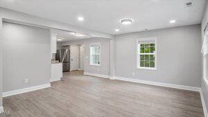 A room with a wood floor and a kitchen.