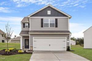 A two-story suburban house at 103 Scoville Street, Oxford, with gray siding, white trim, and black shutters. The front features a double garage, a glass porch door, landscaped grass, shrubs, a young tree, and a partly cloudy sky.