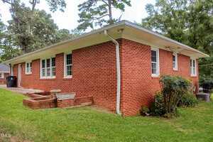 A brick house with a lawn and trees.