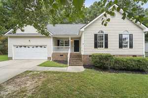 Charming single-story house at 2755 Dorothy Court in Creedmoor with beige siding, black shutters, and a covered front porch. Brick steps lead to the front door, a two-car garage sits on the left, and the landscaping is beautifully maintained.