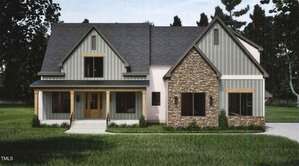 A modern farmhouse-style home at 1121 Dovefield Lane in Youngsville features a covered front porch, grey board-and-batten siding, a gabled roof, and stone facade, all surrounded by lush grass and trees.