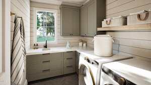 A laundry room with a front-loading washer and dryer, light green cabinets, a window, countertop with cleaning supplies, baskets on a wooden shelf, shiplap walls, and herringbone-patterned floor tiles.