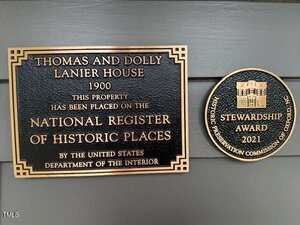 Two plaques on a wall; the left plaque states the Thomas and Dolly Lanier House is on the National Register of Historic Places, and the right plaque is a 2021 Stewardship Award from Oxford, NC's Historic Preservation Commission.
