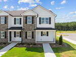 A two-story townhouse at 1106 Brookrun Drive, Oxford, features stone and white siding, black shutters, and a covered front porch. The landscaped yard includes grass and small shrubs, with a driveway visible on the right.