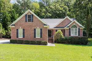 A single-story red brick house with white trim and black shutters sits at 2030 Lonesome Dove Drive in Franklinton, featuring a front porch, green lawn, mature trees, and a driveway on the left.