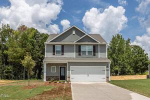 A two-story Oxford-style suburban house at 1008 Rhino Bend features a gray exterior with white trim, a double garage, and a partially landscaped front lawn. Trees and greenery surround the home beneath a partly cloudy sky.