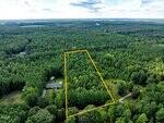 Aerial view of a wooded area in Henderson with a 1.52 Acre Jordan Lane plot outlined in yellow, dense trees throughout, and a house near the bottom left corner, all surrounded by lush forest and greenery.
