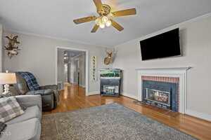 A living room with a fireplace and a ceiling fan.
