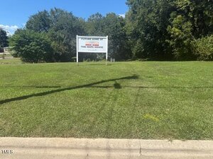 A grassy lot at 312 Sycamore Street in Oxford features a white sign reading "Future Home Of The Hope House." Trees and bushes surround the area, and a sidewalk runs along the foreground.