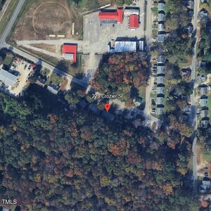 Aerial view of 228 Crozier St, showing a forested area in the lower half, a residential street on the right, and some commercial buildings with parking lots at the top of the image. A red location pin marks the address.