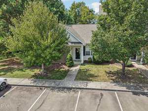 A single-story house at 301 Winston Way, Creedmoor, with a gray roof and white trim, is partially obscured by two trees in the front yard. A concrete walkway leads to the front door, with parking spaces visible in the foreground.