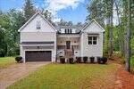 A two-story white house at 4535 Gresham Drive, Oxford, features a dark double garage, front porch with stairs, shrub landscaping, and is surrounded by tall trees and a grassy yard under a partly cloudy sky.