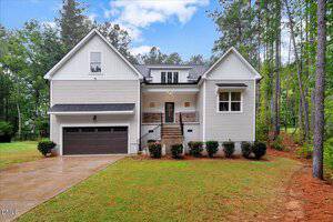 A two-story white house at 4535 Gresham Drive, Oxford, features a dark double garage, front porch with stairs, shrub landscaping, and is surrounded by tall trees and a grassy yard under a partly cloudy sky.