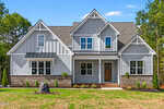 Located at 3919 Cedar Knolls Drive in Youngsville, this two-story modern farmhouse features gray siding, white trim, a brick foundation, and a covered front porch. Multiple gables and a brown front door complete the inviting curb appeal.