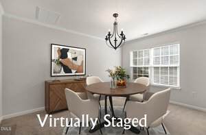 A virtually staged dining room features a round table with four white chairs, a sideboard with abstract art above it, a black chandelier, and a window allowing natural light into the neutral-toned room. The text reads "Virtually Staged.