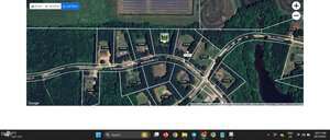 A satellite map view shows a wooded residential neighborhood with property lines and property values labeled. Roads curve through the area, and individual houses and driveways are visible among trees.