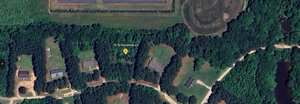 A satellite view shows a forested rural area with a few scattered buildings and dirt roads. A yellow marker pinpoints "74 N Hacienda Ln" at a property surrounded by trees. Fields and open grassy areas are visible nearby.
