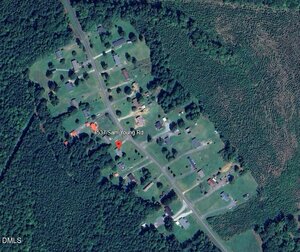 Aerial view of a rural neighborhood with scattered houses, lawns, and trees along Sam Young Road. A red location marker pinpoints 1537 Sam Young Rd. Dense green forest surrounds the residential area.