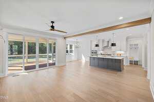 A large white and grey kitchen with a wood floor and ceiling fan.