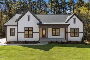 A modern single-story house at 280 Stonewood Loop Lane, Henderson, featuring white siding, black trim, and a dark gray roof. The front porch has wooden posts, a neatly maintained lawn, and tall trees in the background.