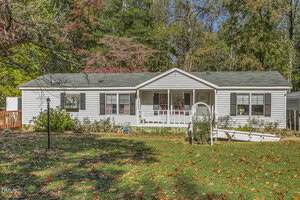 A single-story white house with black shutters at 3663 Chewning Road, Oxford features a covered front porch and a gray shingled roof, surrounded by trees and a grassy yard dotted with autumn leaves.
