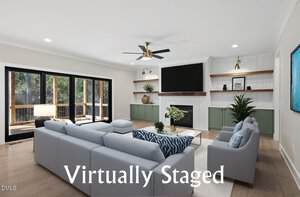 A modern living room with a light gray sectional sofa, two armchairs, a fireplace with a mounted TV, wood shelves, and large sliding glass doors to a deck. "Virtually Staged" text appears across the image.