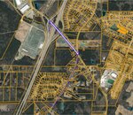 Aerial map with yellow property lines overlaid; a thick lavender line highlights a path crossing a highway near 1689 Will Suitt Road, extending through residential and wooded areas, intersecting roads and neighborhoods.