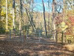 A metal gate blocks a leaf-covered dirt path in a wooded area near 0 Hillandale Drive, Oxford. A yellow "Dead End" sign is mounted on a post beside the gate, with autumn foliage adorning the trees in the background.