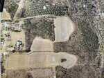 Aerial view of a rural Henderson area showing fields, wooded areas, property boundary lines, and several buildings near a road on the left side. The 20.37 Acre Opie Frazier tract is labeled, along with other markings on the image.