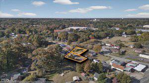 Aerial view of a suburban neighborhood with houses, trees, and roads. Two adjacent vacant lots are outlined in orange near the center-right, distinguishing them from surrounding properties.