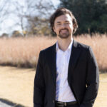 Avatar image for Cameron Saemann Thumbnail sized image of Cameron Saemann standing outside near a walkway in a field.