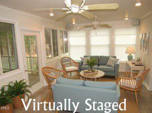 A sunroom with large windows, tiled floors, and neutral walls, furnished with light blue sofas, rattan chairs, a round coffee table, side table with lamp, decor accents, ceiling fans, and "Virtually Staged" text overlaid.