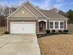 Single-story suburban house at 2726 Spring Valley Drive in Creedmoor, featuring a two-car garage, stone and siding exterior, red front door, multiple front windows, manicured lawn, trimmed shrubs, driveway, and welcoming walkway to the entrance.